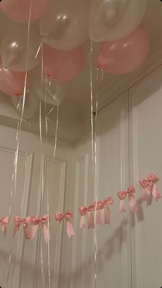 balloons and streamers are hanging from the ceiling in front of a white door with pink bows