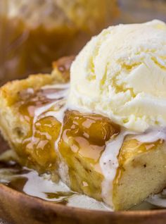 a piece of pie with ice cream on top is in a wooden bowl next to a spoon