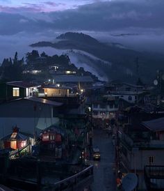 the city is lit up at night with fog in the sky and low lying clouds