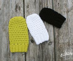 three crocheted mittens laying on top of a wooden table next to each other