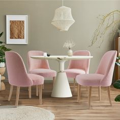 a white table with four pink chairs around it and a rug on the floor next to it