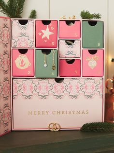 a pink and green christmas card box with ornaments on it next to a candle holder