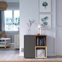 a living room filled with furniture and a book shelf next to a window on top of a hard wood floor