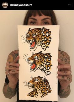 a woman holding up a piece of paper with two pictures of leopards on it