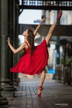 a woman in a red dress is dancing on the sidewalk with her legs spread out