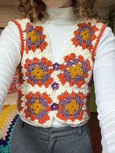 a close up of a person wearing a crocheted vest with flowers on it