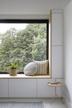 a window seat with pillows and a potted plant