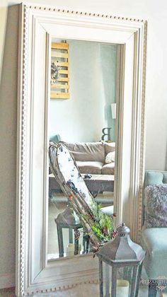 a mirror sitting on top of a table next to a vase filled with green plants