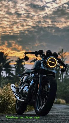 the motorcycle is parked on the side of the road near some grass and palm trees