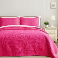 a bed with pink comforter and pillows in a room