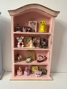 a pink book shelf filled with figurines on top of it's sides