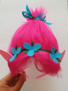 a hand holding a pink hat with blue flowers on it