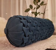 a large blue pillow sitting on top of a table next to a potted plant