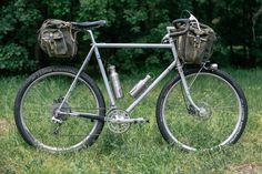 a bike parked in the grass with a backpack on it's back end and front wheel