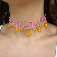 a woman wearing an orange and pink necklace with beads on it's back neck