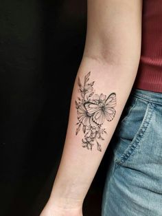 a woman's arm with a butterfly and flowers tattoo on the left inner arm