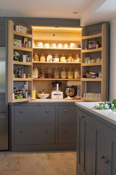 a kitchen with gray cabinets and shelves filled with jars, containers and utensils