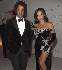 a man in a tuxedo standing next to a woman in a black dress