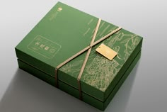 a green box with a gold tag tied to it's side and the lid is open