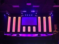 an empty stage with purple lighting and chairs