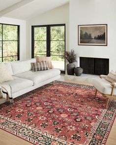 a living room filled with furniture and a large rug on top of a hard wood floor