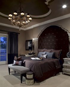 a bedroom with a large bed, chandelier and two chairs in front of it