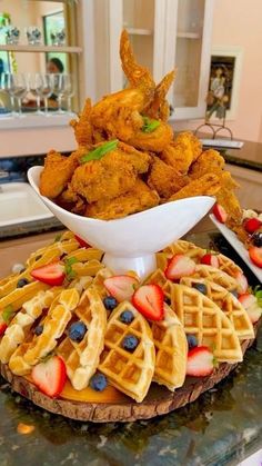 some waffles and strawberries are on a table with other foods in the background