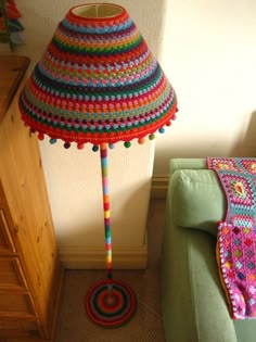 a crocheted lamp shade sitting on top of a green couch in a living room