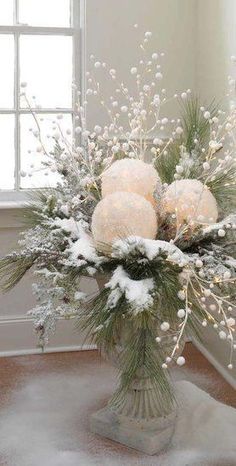 a vase filled with white flowers on top of a wooden floor next to a window