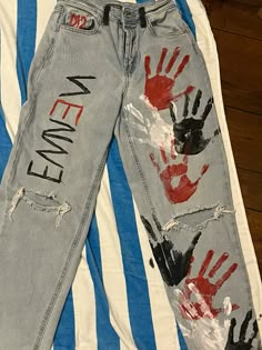 two pairs of jeans with handprints on them sitting on top of a blue and white striped shirt