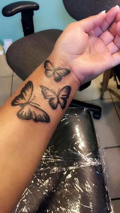 a woman's arm with three butterflies tattooed on the left side of her wrist