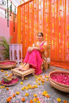 a woman sitting on a chair in front of a stage with flowers all over the floor