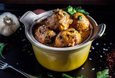 a yellow bowl filled with meatballs and garnished with parsley on the side