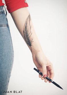 a woman with a feather tattoo on her arm holding a knife and pointing it at the camera