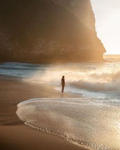 a person standing in the surf on a beach