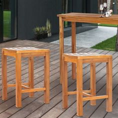 two wooden stools sitting next to each other on top of a wooden patio floor