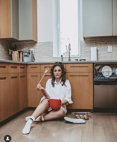 a woman sitting on the floor with a brush in her hand