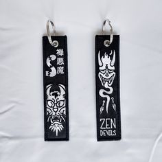 two black and white key chains with designs on them