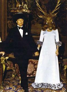 a man and woman dressed in formal wear standing next to an antelope mask