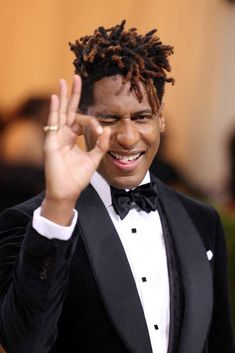 a man in a tuxedo making the vulcan sign with his hand and smiling