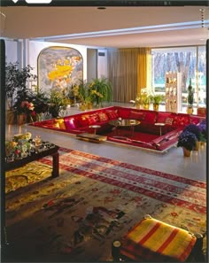 a living room filled with lots of red couches next to a large painting on the wall