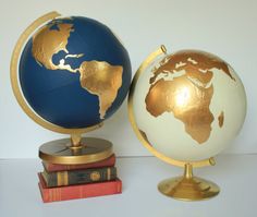 a blue and gold globe sitting on top of two red bookends next to each other