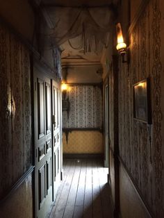 an empty hallway leading to another room with wall papered walls and wood flooring