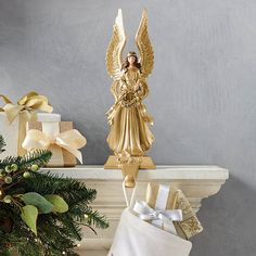 a gold angel figurine sitting on top of a mantle next to christmas presents