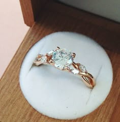 an engagement ring with three stones in it sitting on top of a white display case