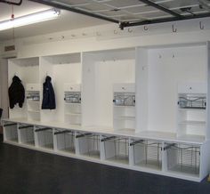 an empty room with several white shelves and clothes hanging on the wall in front of them