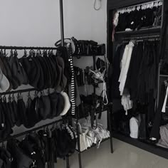 a closet filled with lots of black and white clothing hanging on the wall next to a mirror