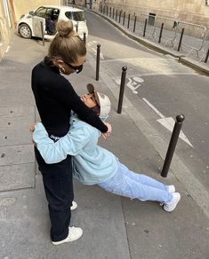 two people are hugging on the street