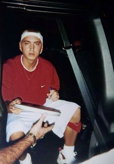 a man sitting in the back seat of a car holding a clipboard and pen