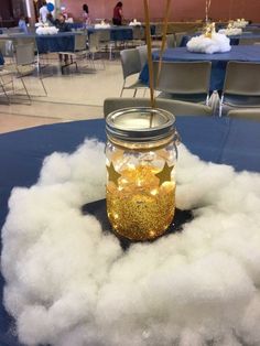 a mason jar filled with cotton balls on top of a blue tablecloth covered in white fluffy